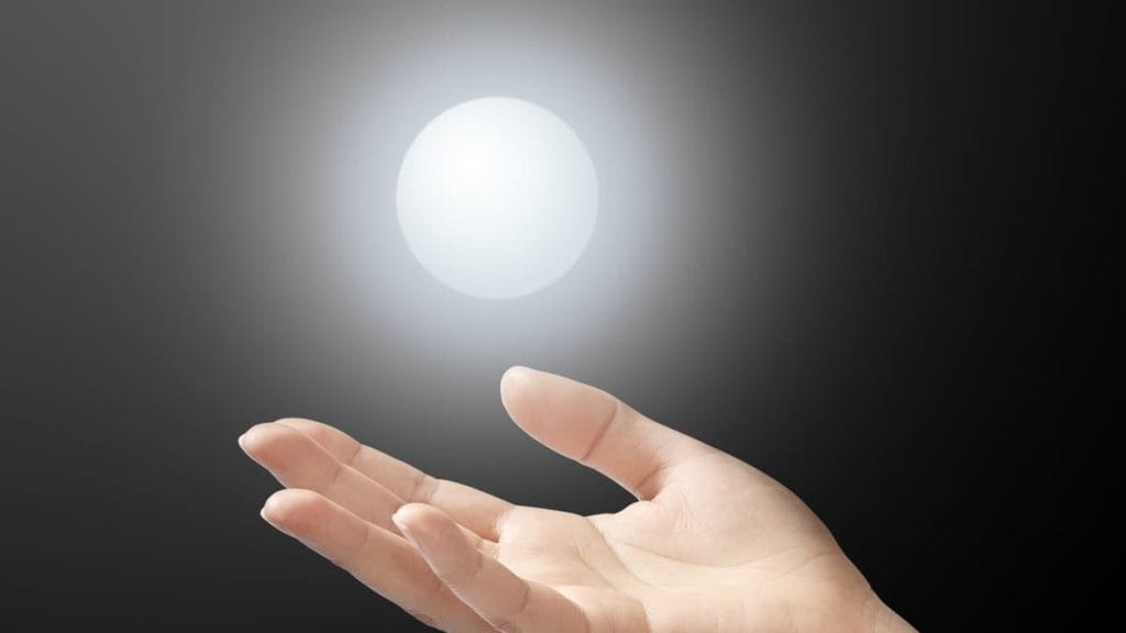 手のひらを上に向けて開いた手は、暗い背景の中で白く光る球体を支えているようにも、手を伸ばしているようにも見える。